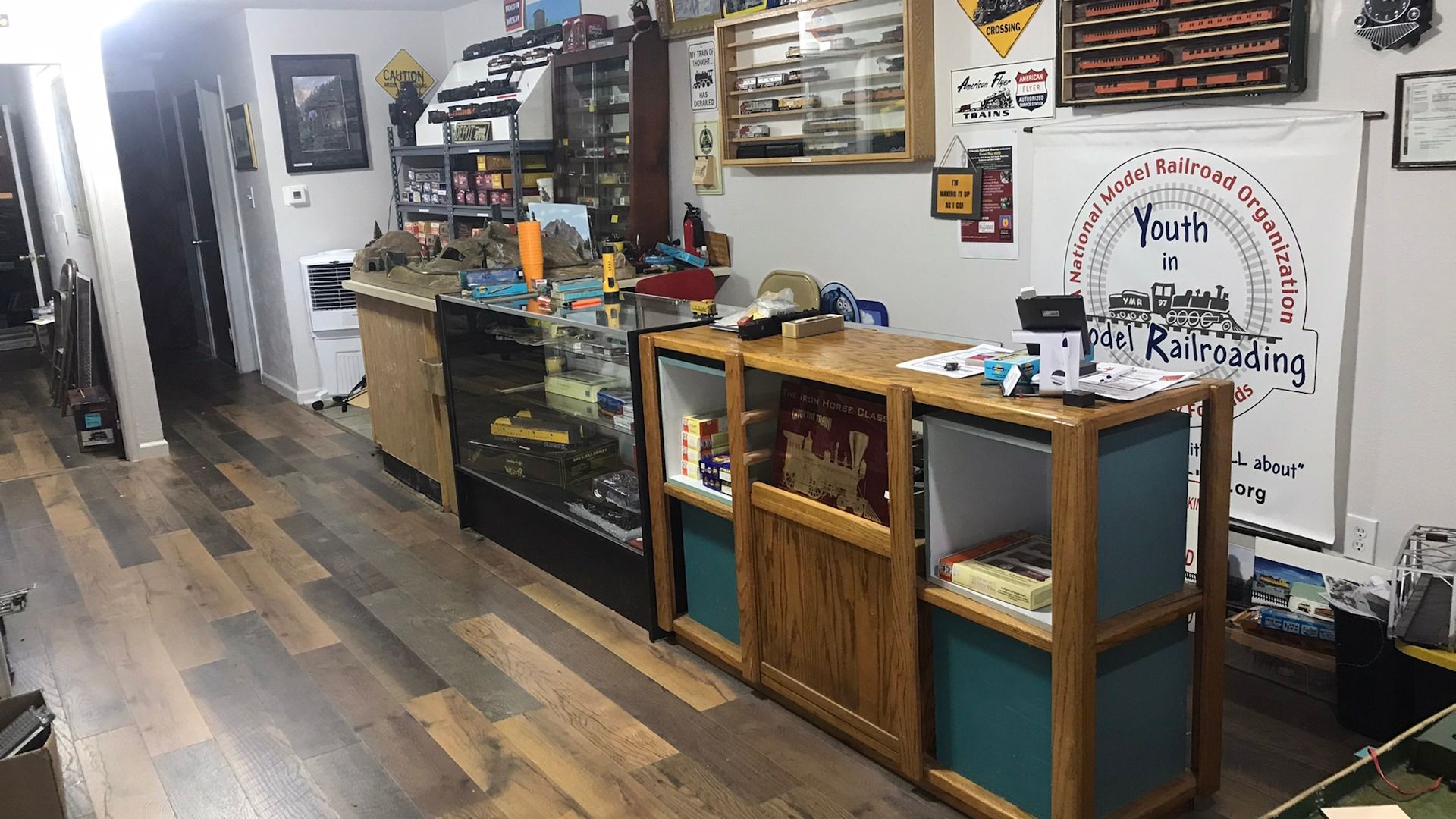 A room with wooden floors , shelves , and a display case.