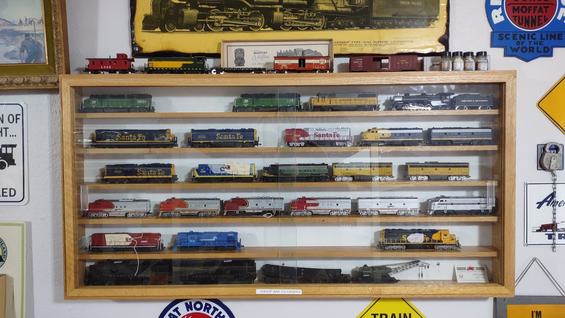 A display case filled with toy trains and signs including one that says 