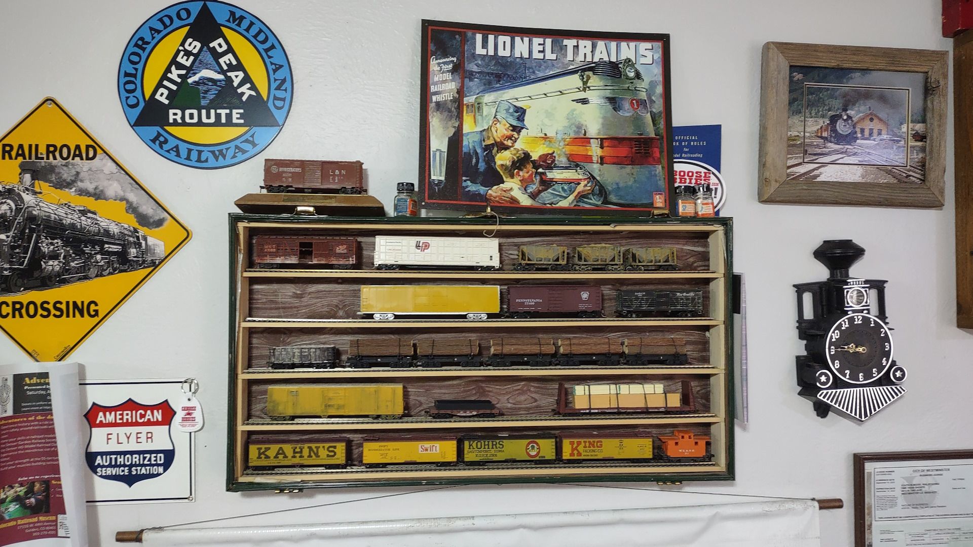 A shelf filled with train cars and a sign that says railroad crossing