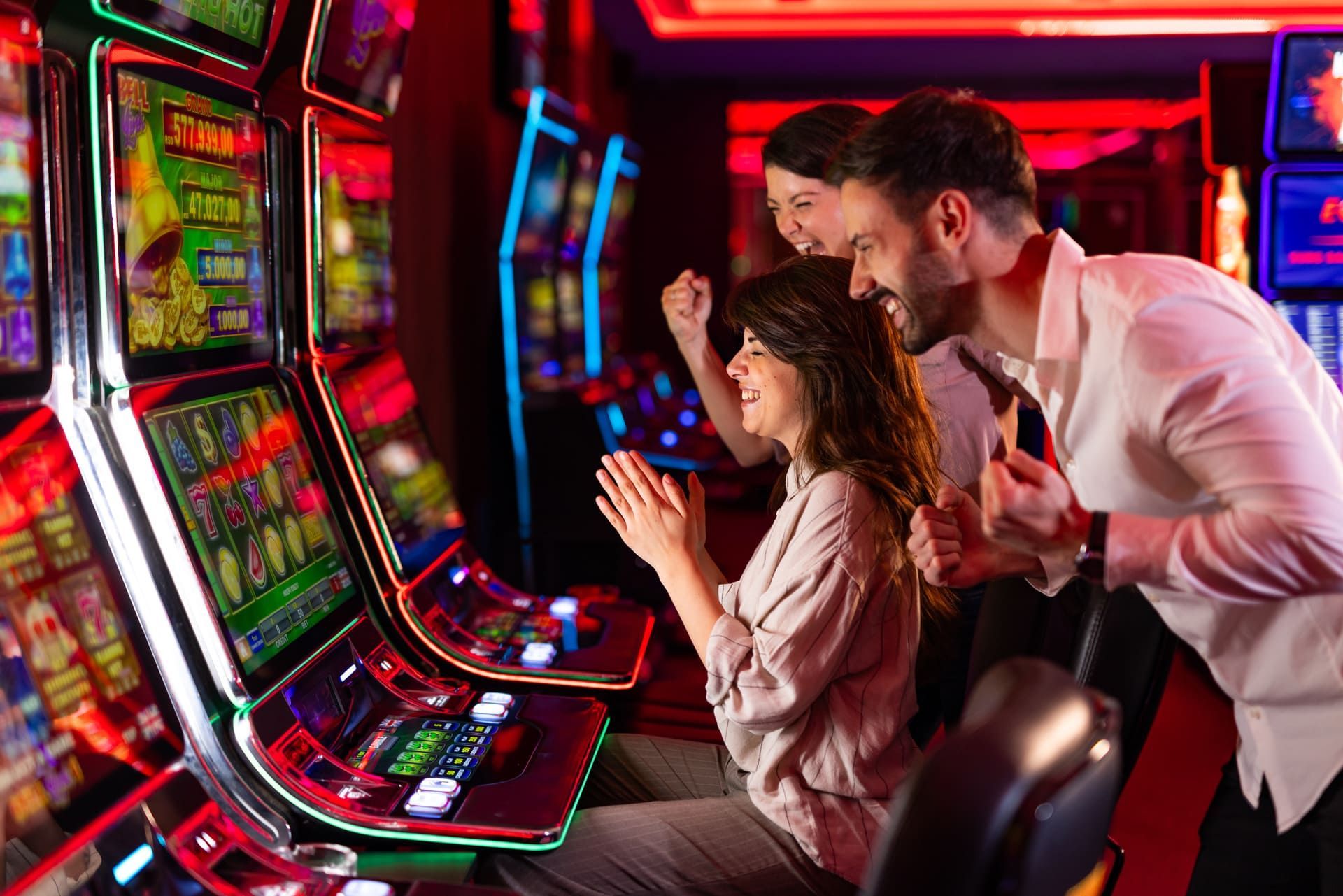 Friends Celebrating Success at Casino Slot Machines With Vibrant Lights
