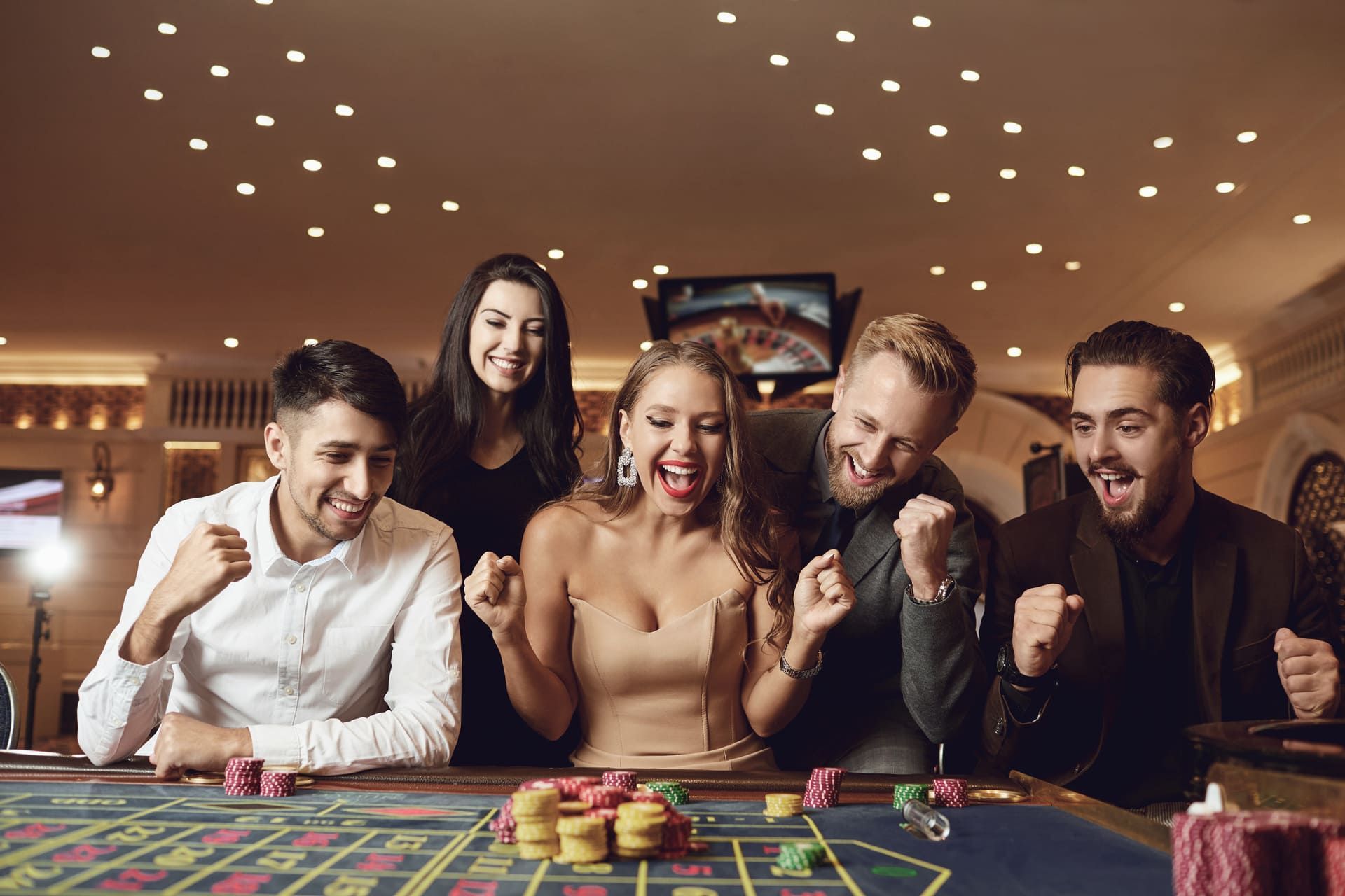 Happy people are betting in gambling at roulette poker in a casino