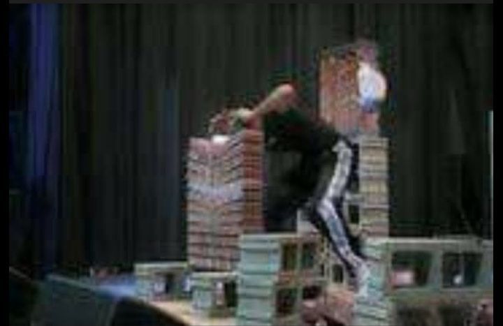 A man is doing a trick on a stage in front of a crowd.