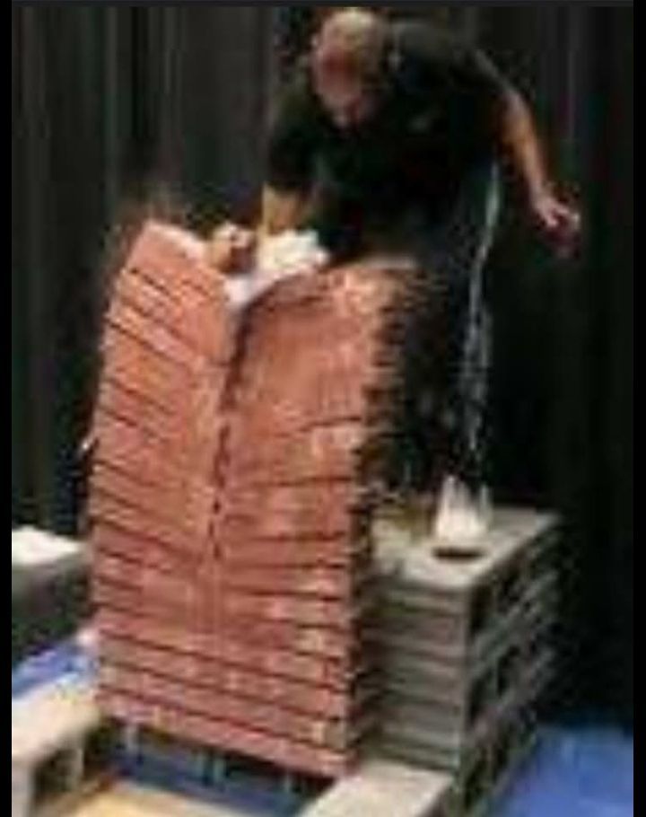 A man is standing next to a pile of bricks.