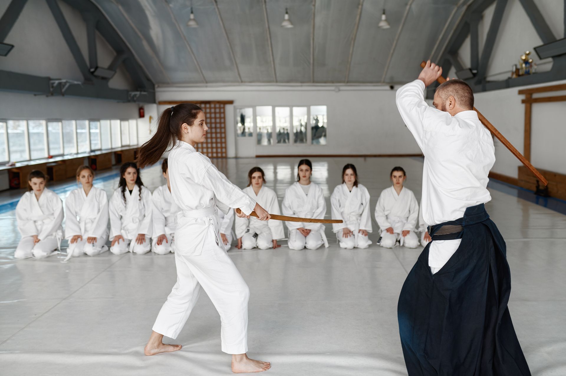 A man and a woman are practicing aikido in a gym.