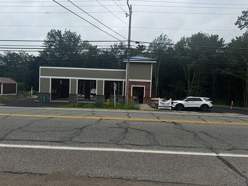 Car wash building along a road with a white SUV parked in front.