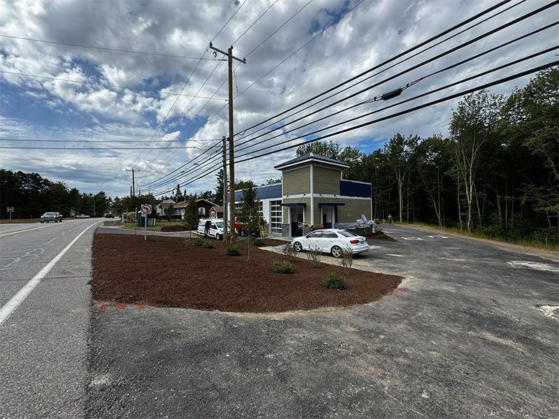 A building with a blue and beige facade, a car parked in front, and a power pole.