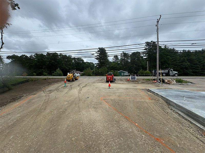 Construction site: two mini excavators on gravel, cloudy sky, power lines.