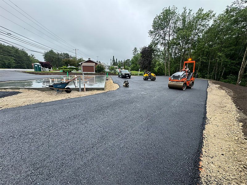 Asphalt paving construction site with rollers compacting fresh black asphalt.