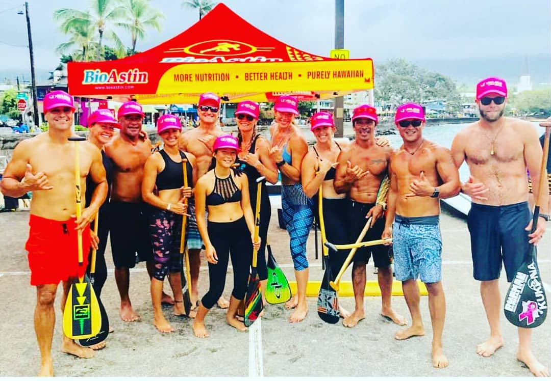 A group of people are posing for a picture in front of a red and yellow tent.
