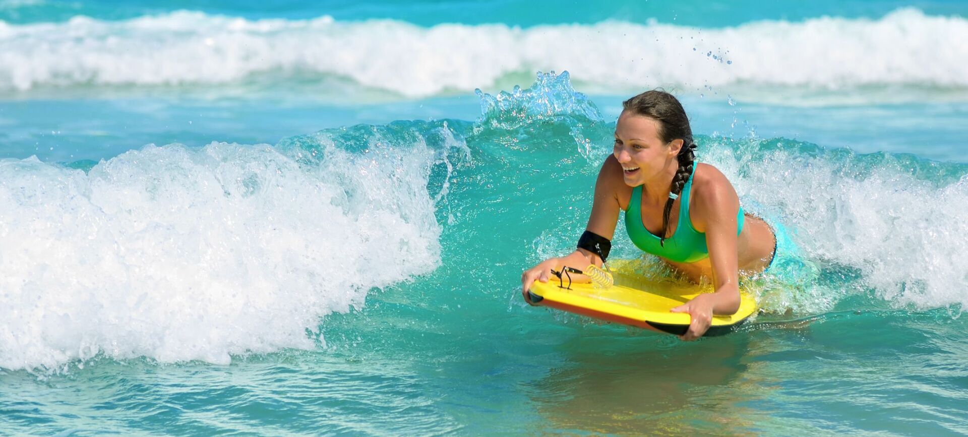 A woman is riding a wave on a boogie board in the ocean.