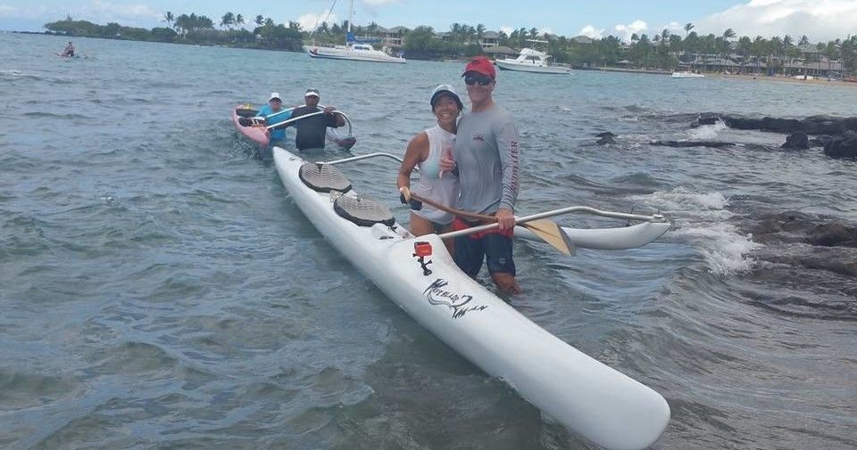 A man and a woman are in a white kayak in the water