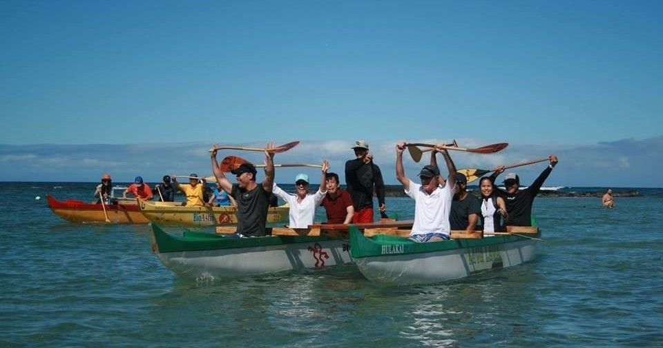 A group of people are rowing boats in the ocean.