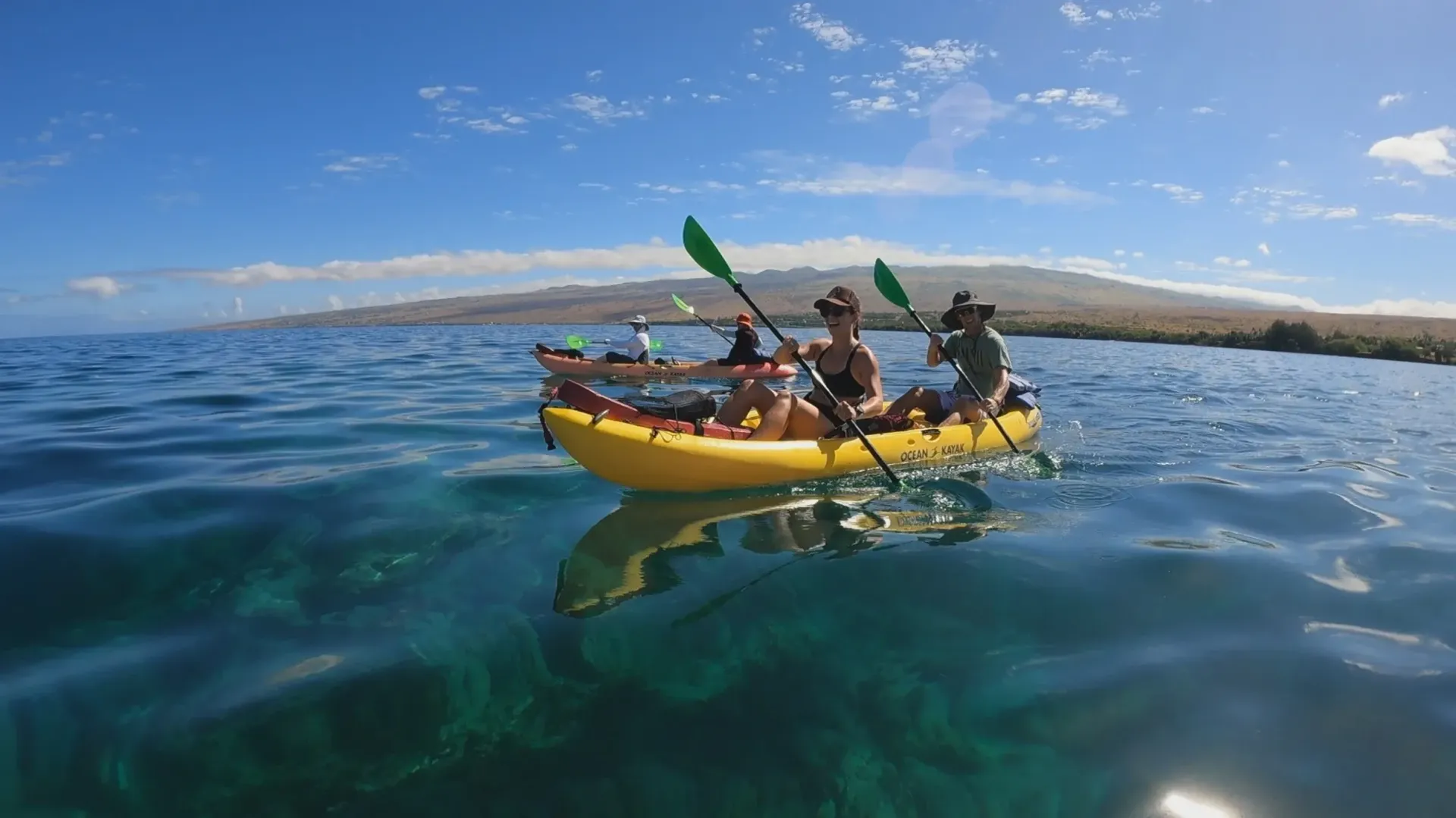 A group of people are paddling a yellow kayak in the ocean.