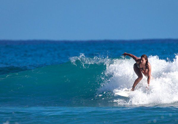 A woman is riding a wave on a surfboard in the ocean.