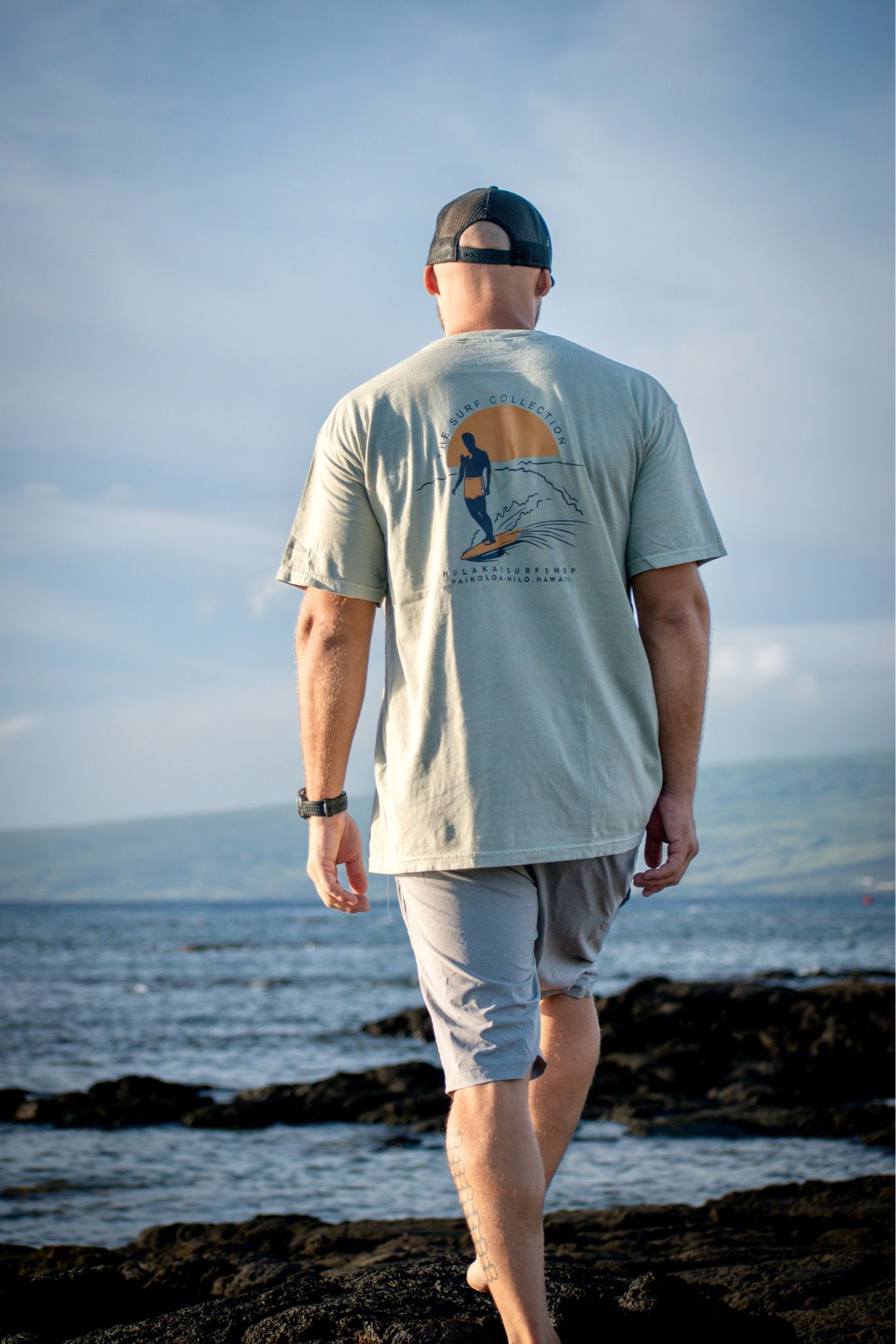 A man in a t-shirt and shorts is walking on the beach.
