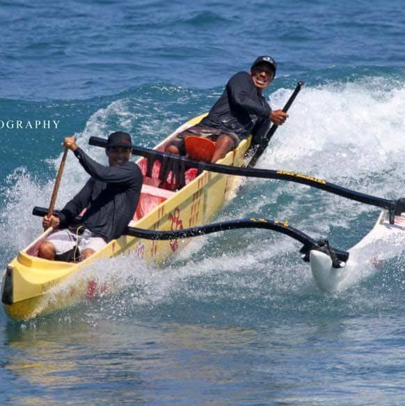 Two men are paddling a yellow boat in the ocean