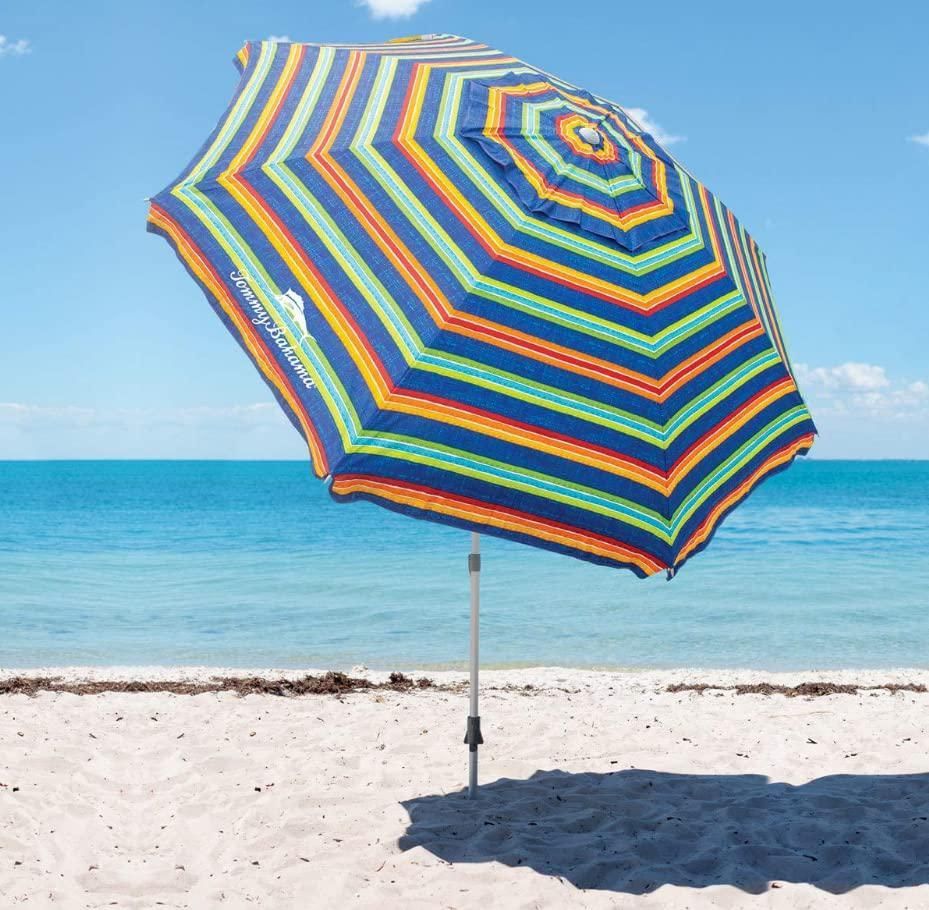 A colorful striped umbrella on a beach with the ocean in the background