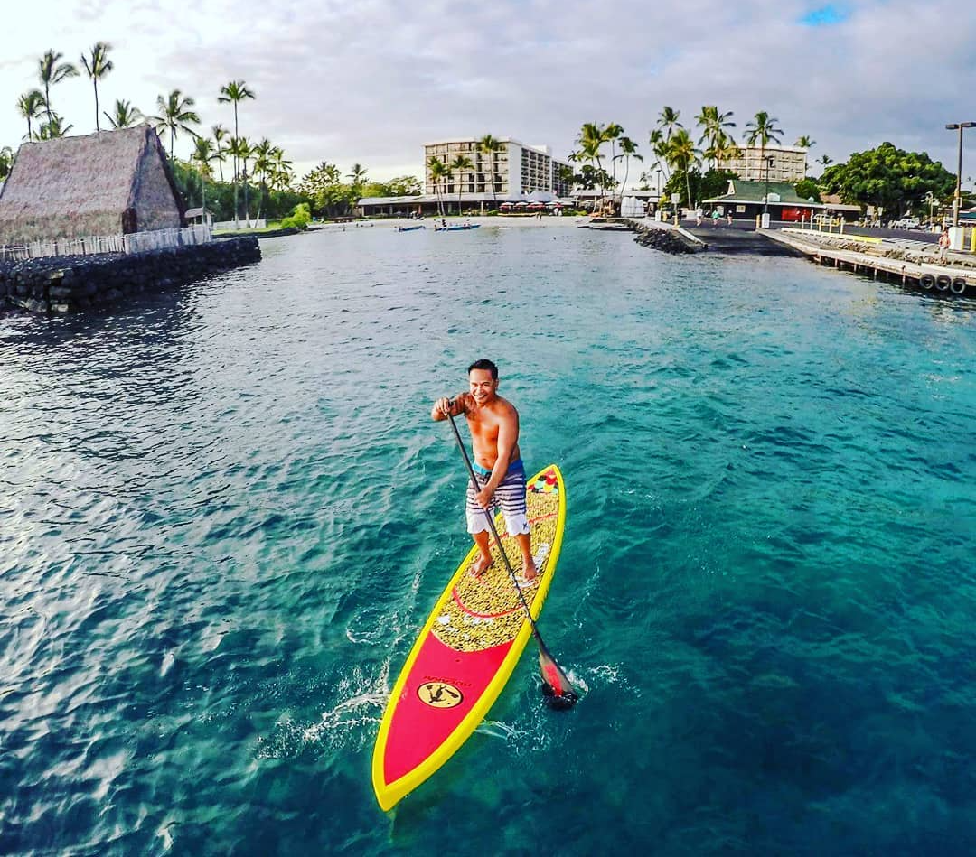 A man is riding a paddle board in the ocean