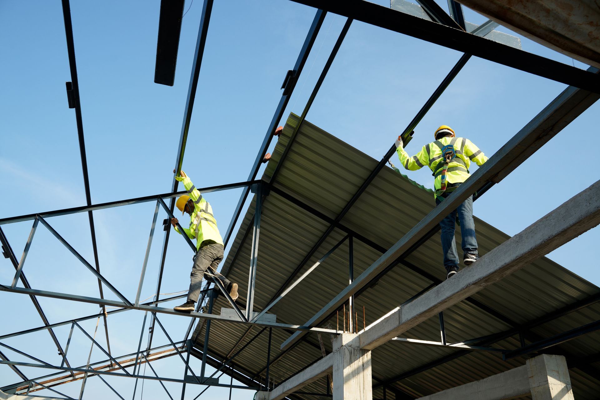Two construction workers are working on the roof of a building.