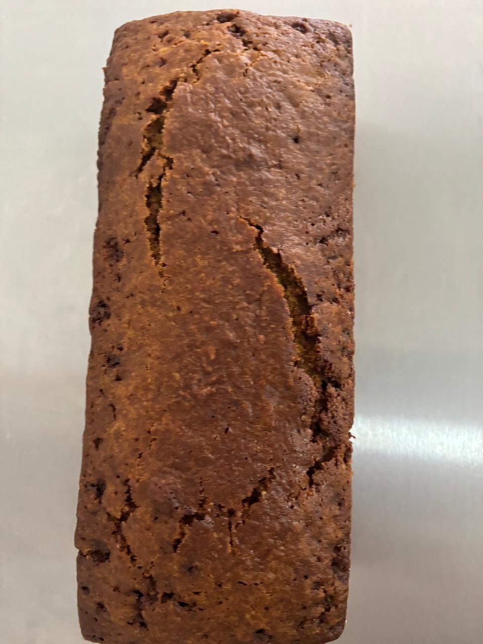 Bizcocho en molde de plata sobre rejilla, con paño de cocina blanco.