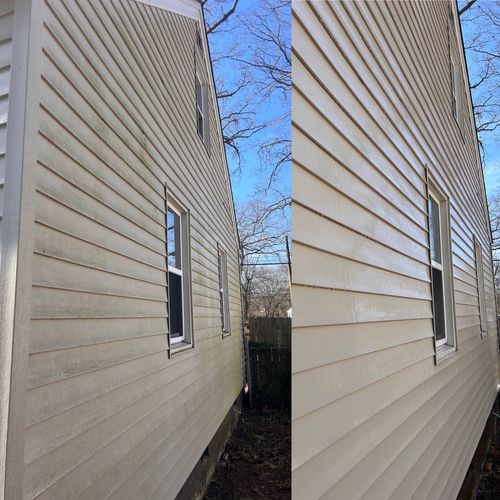 A person is using a pressure washer to clean the side of a house.