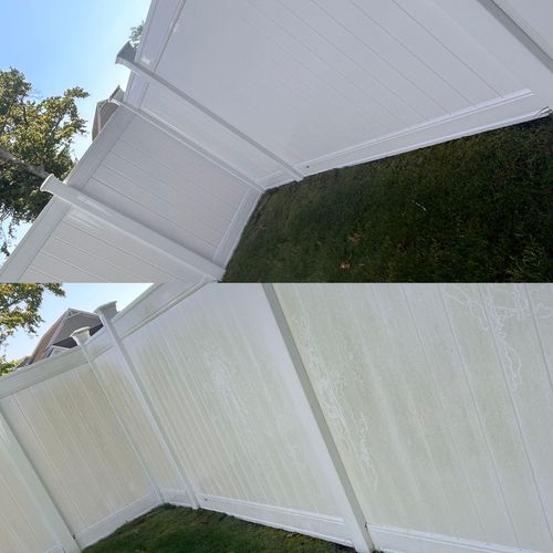 A person is cleaning a wooden fence with a high pressure washer.