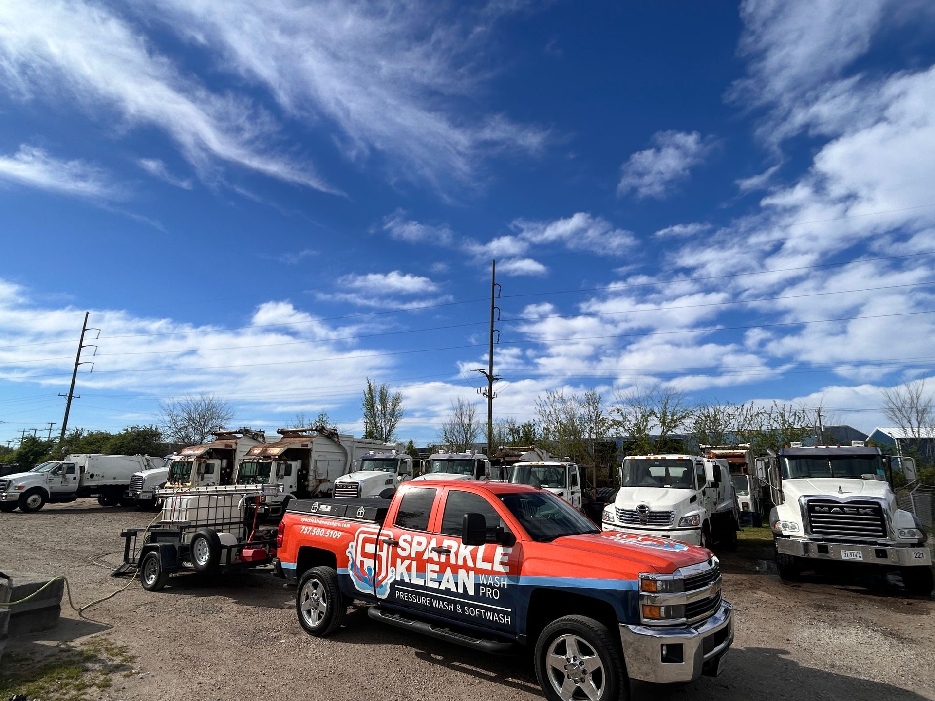 A red truck is parked in a lot with other trucks.