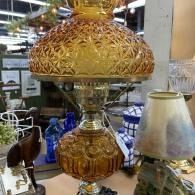 Decorative gold table lamp with patterned shade displayed among other lamps in a shop