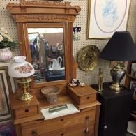 Antique wooden vanity with mirror, table lamps, and decorative items in a vintage room.