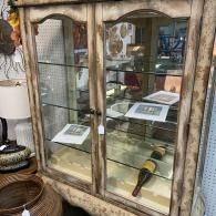Old wooden display cabinet with glass shelves holding knives and papers in a rustic shop.