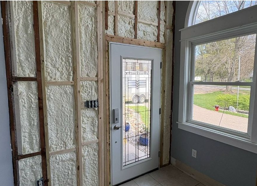 Interior wall with spray foam insulation; door with glass panes; window with outside view.