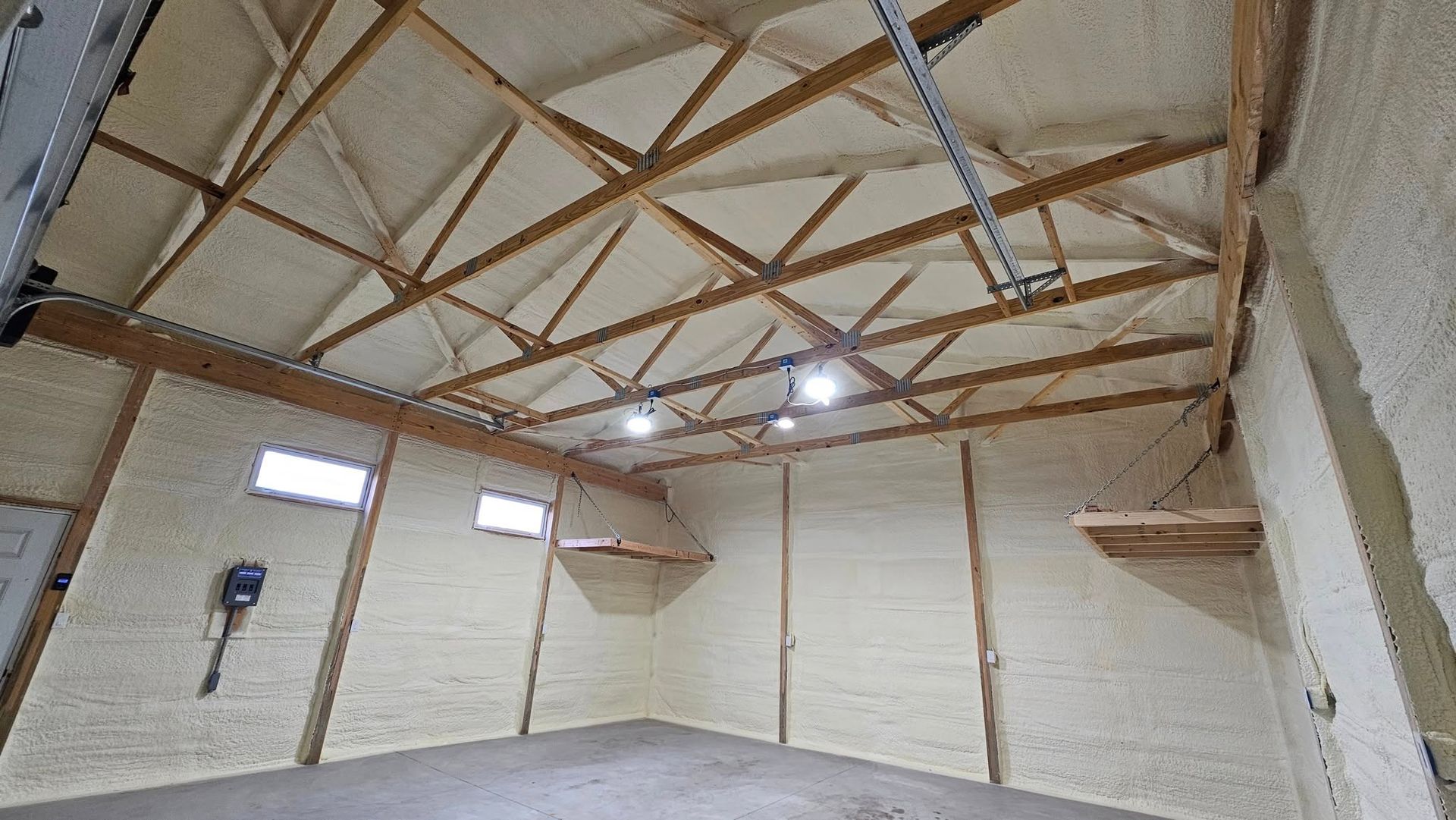 Interior of a building with exposed wooden rafters, coated in insulation.