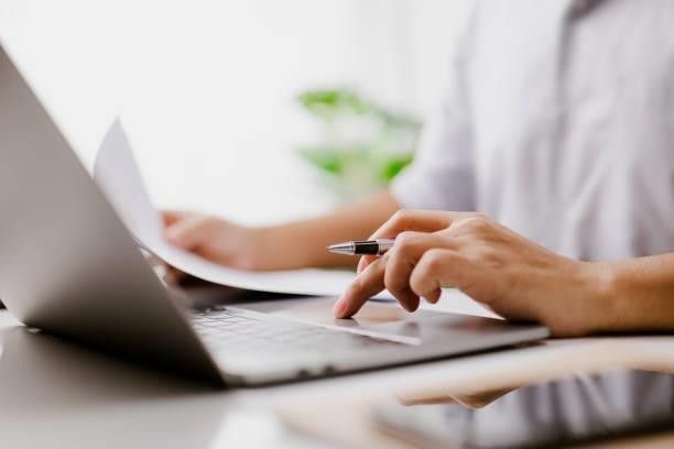 A person is using a laptop computer while holding a pen.