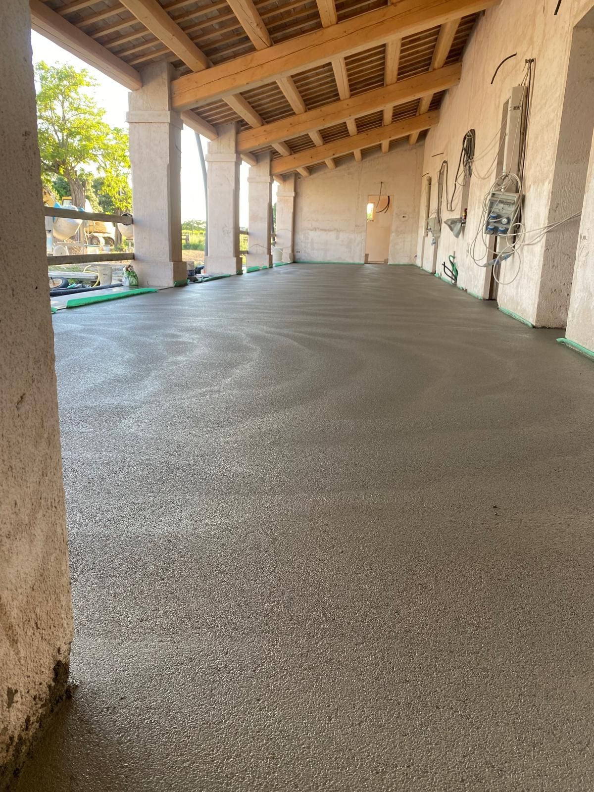 Cucina e sala da pranzo con pareti in mattoni a vista, tavolo bianco e sedie grigie. Finestre luminose e lampade a sospensione.