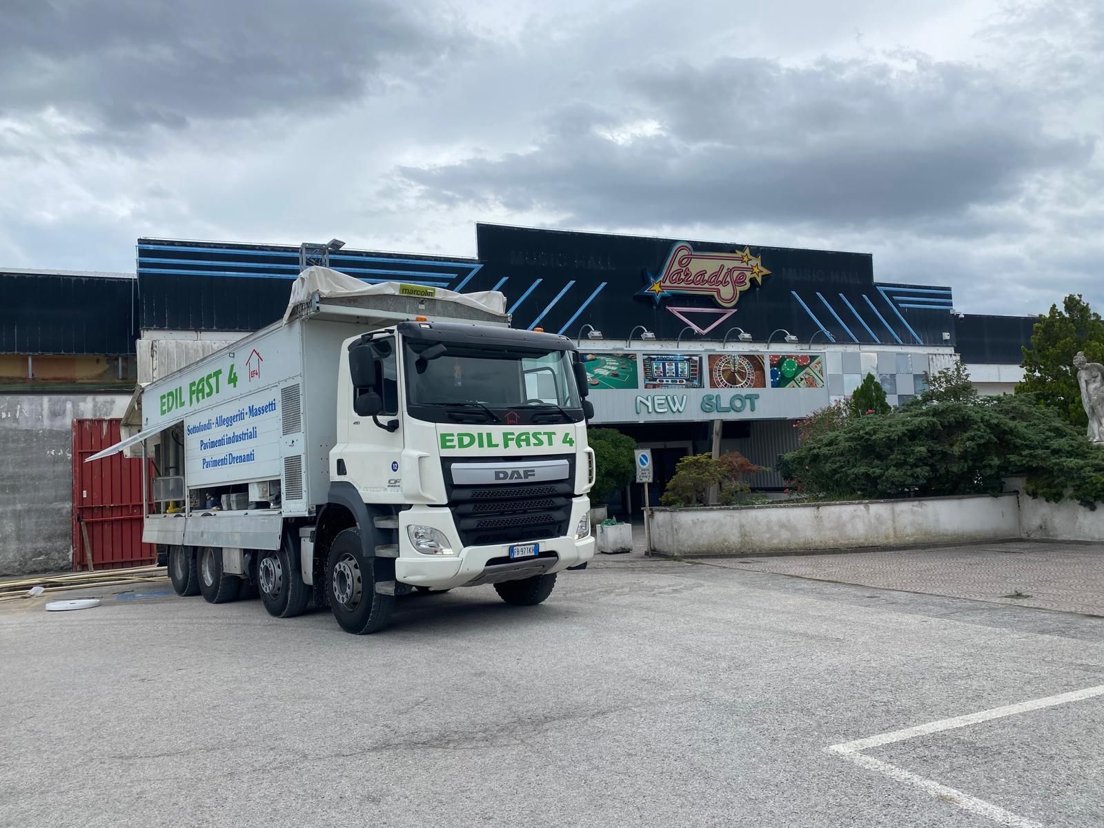 Edificio in fase di ristrutturazione nella piazza di una città italiana, impalcature sulla sinistra, tramonto sullo sfondo.
