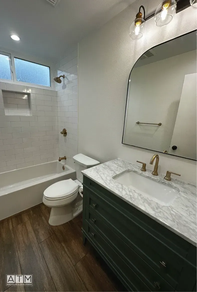 A bathroom with a toilet , sink , bathtub and mirror.