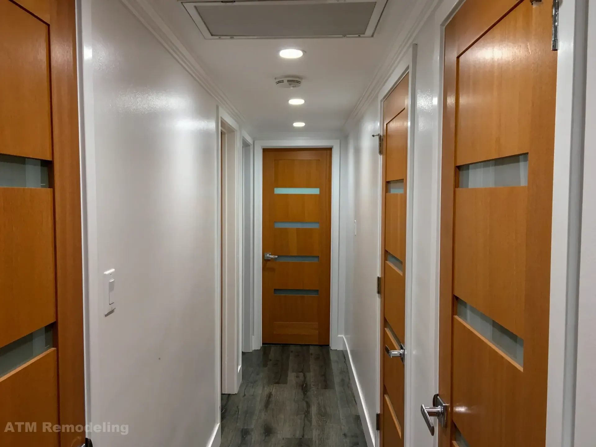 A long hallway with wooden doors and white walls