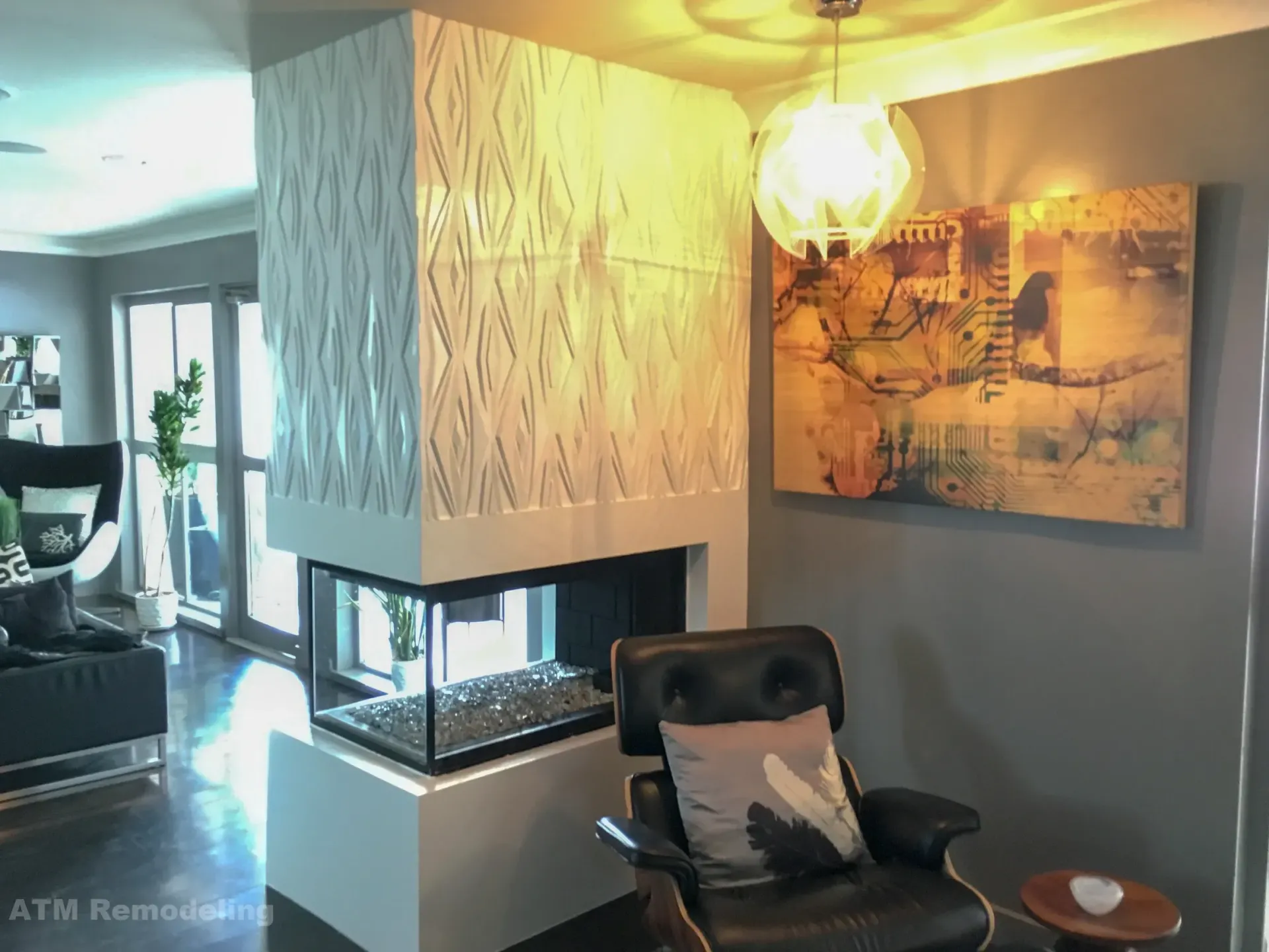 A living room with a fireplace and a chair and a painting on the wall.