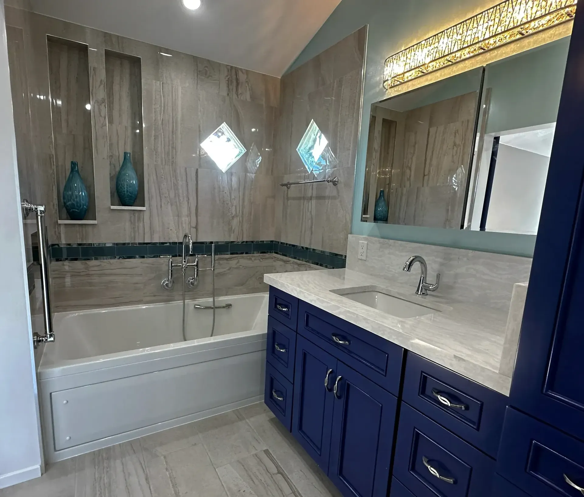 A bathroom with blue cabinets , a sink , and a bathtub.