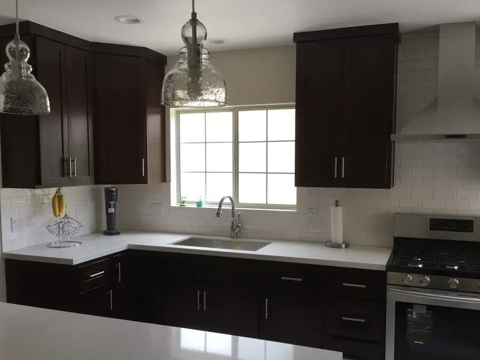 A kitchen with dark cabinets and white counter tops