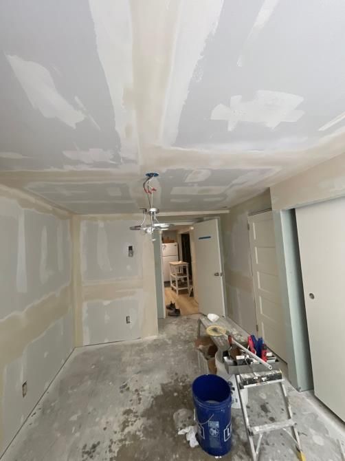 Room under renovation with unfinished drywall, ceiling fan, and tools.