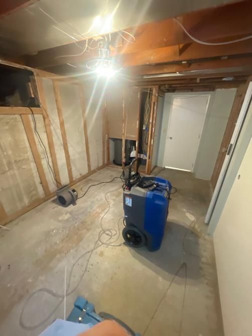 Basement undergoing renovation; dehumidifier and blower on concrete floor.