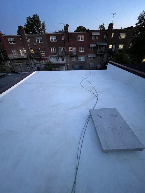 A white roof with a brick building in the background.