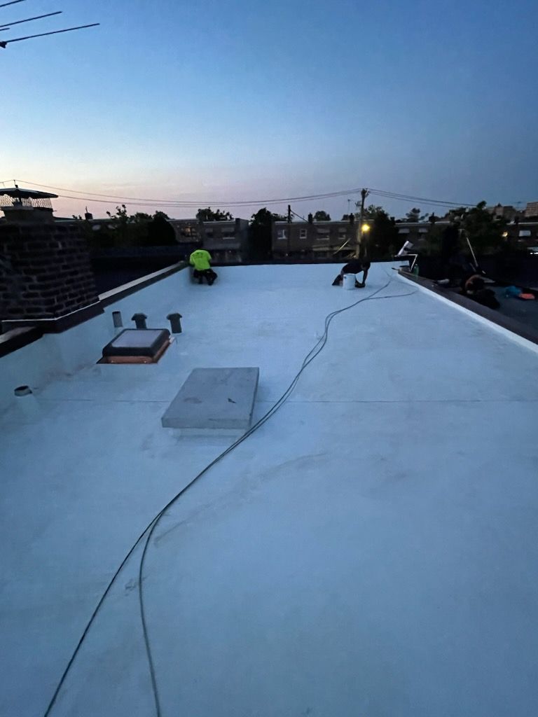 A man is working on a white roof at night.