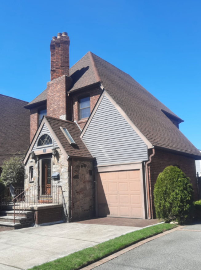 Brick house with angled roof, attached garage, and stone facade entrance.