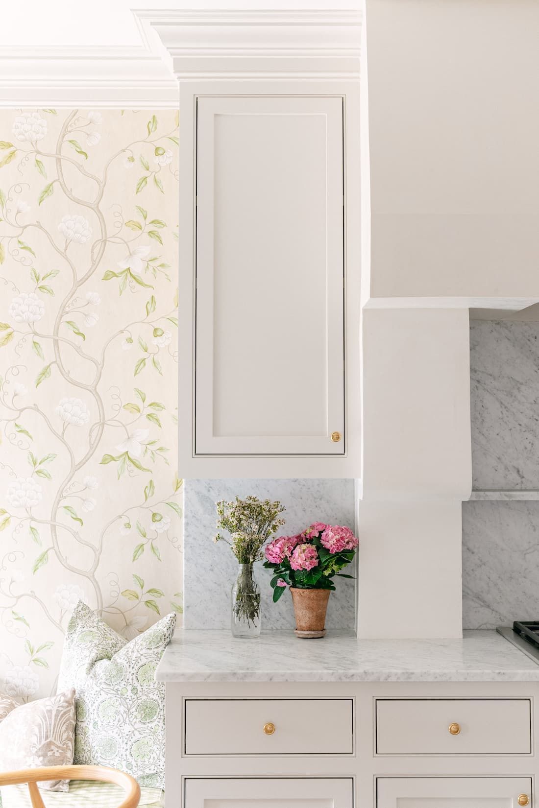 There is a vase of flowers on the counter in the kitchen.