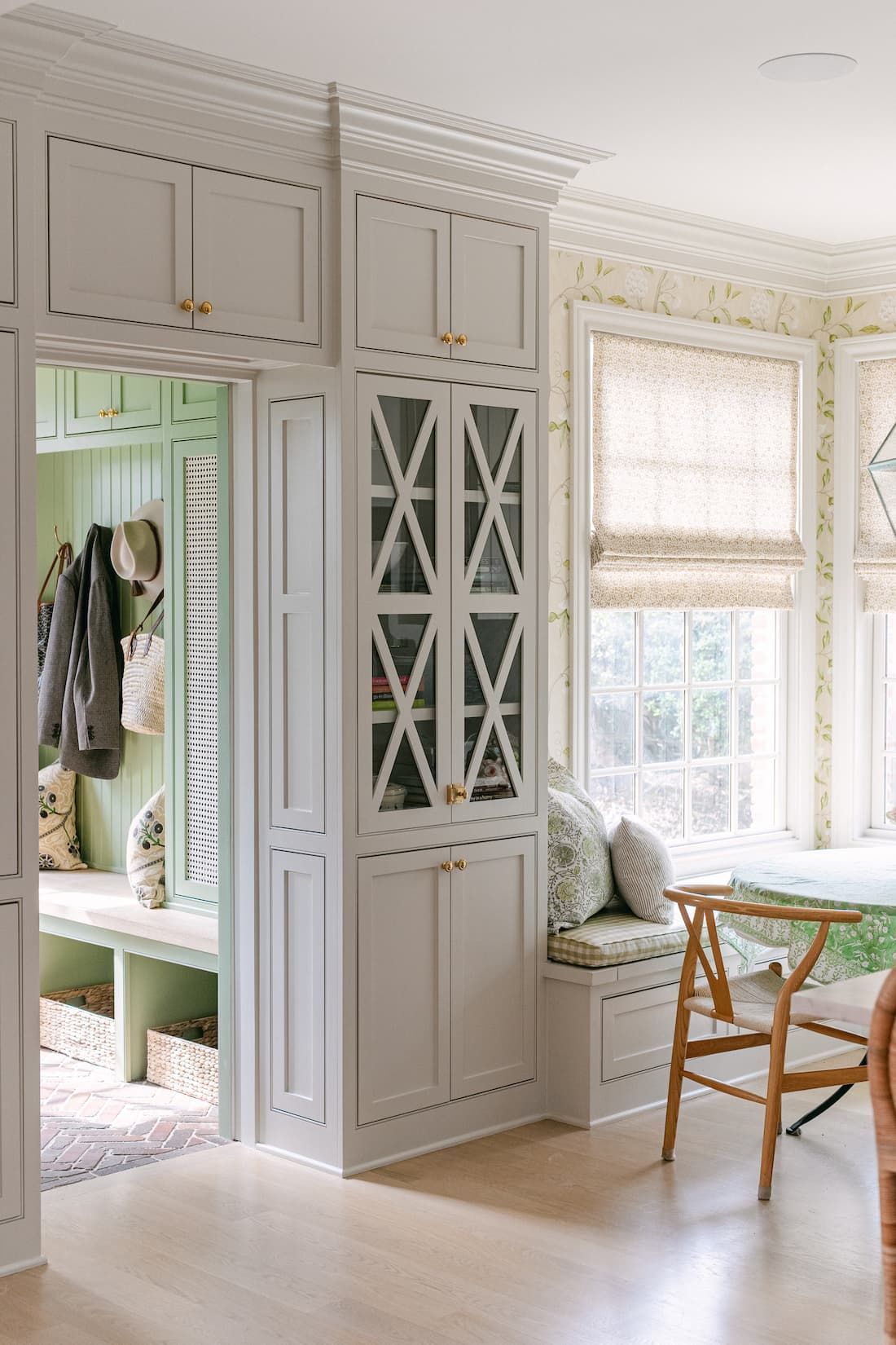 A room with custom wood white cabinets , a bench , a table and chairs.