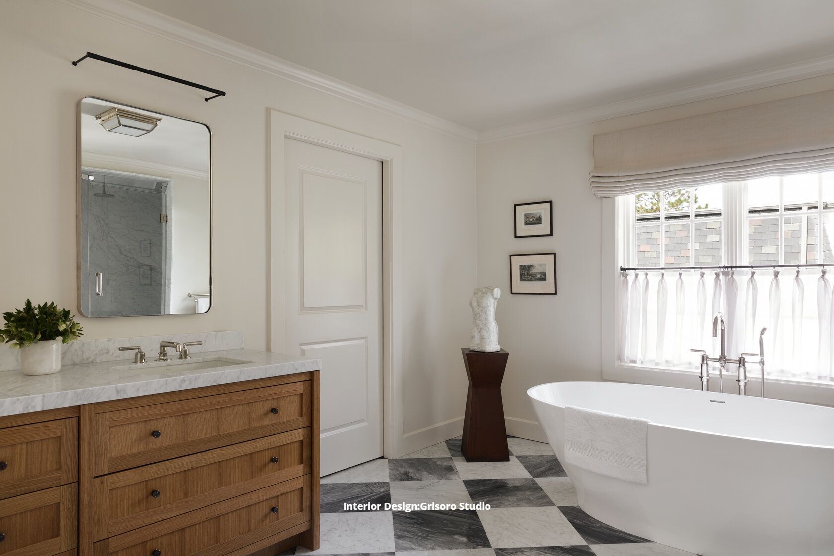 A remodeled bathroom with a bathtub, sink, mirror and checkered tile floor.