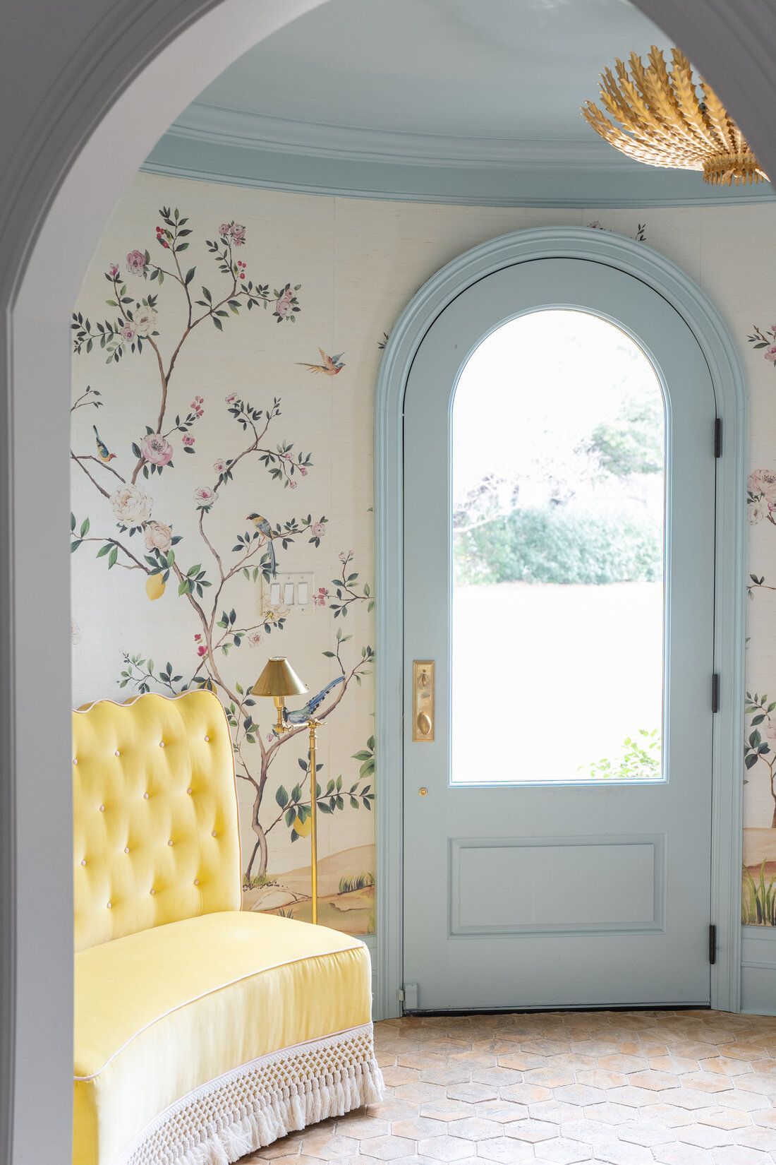 A hallway with a yellow couch and a blue door.
