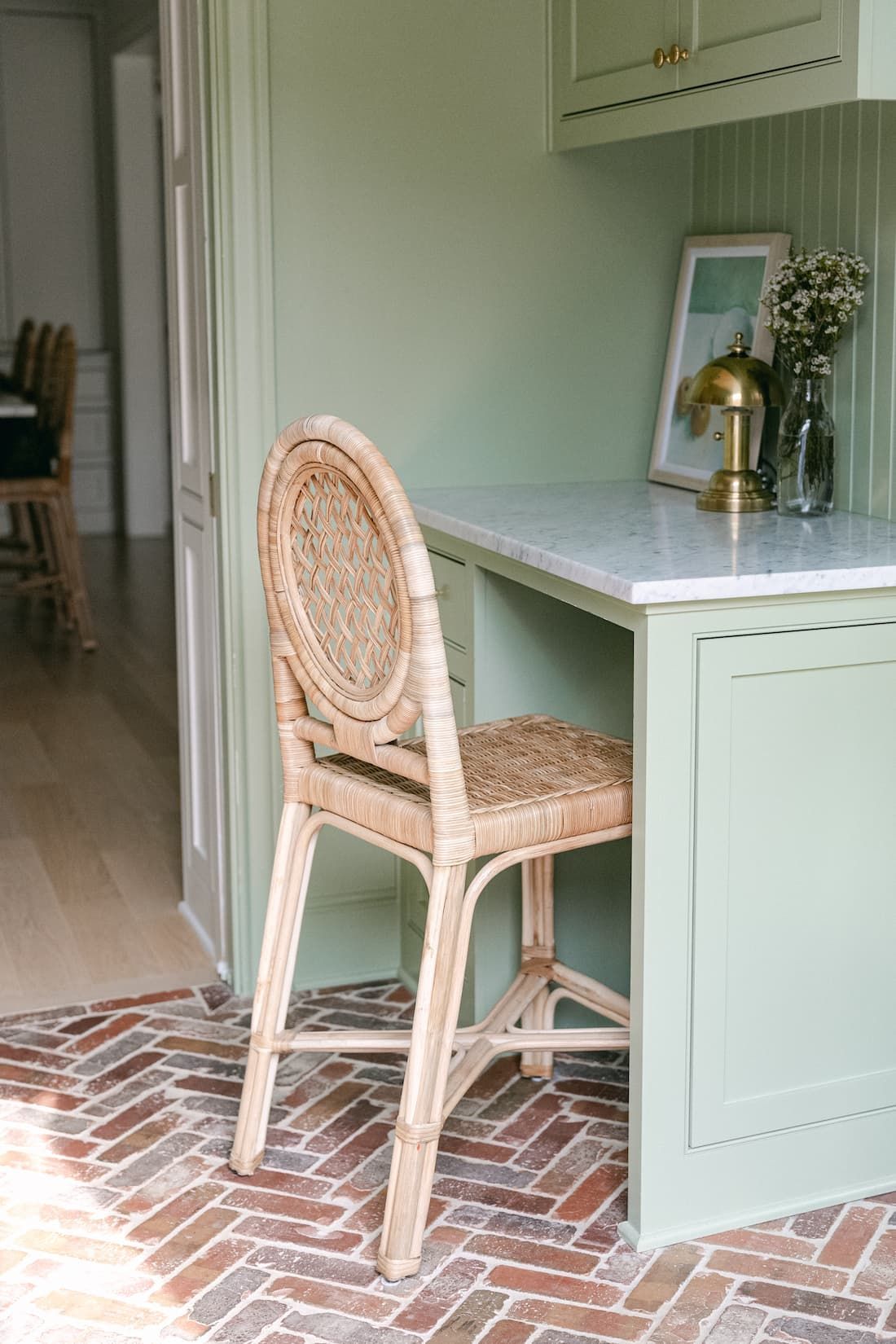 A wicker chair is sitting next to a built in desk in a kitchen.